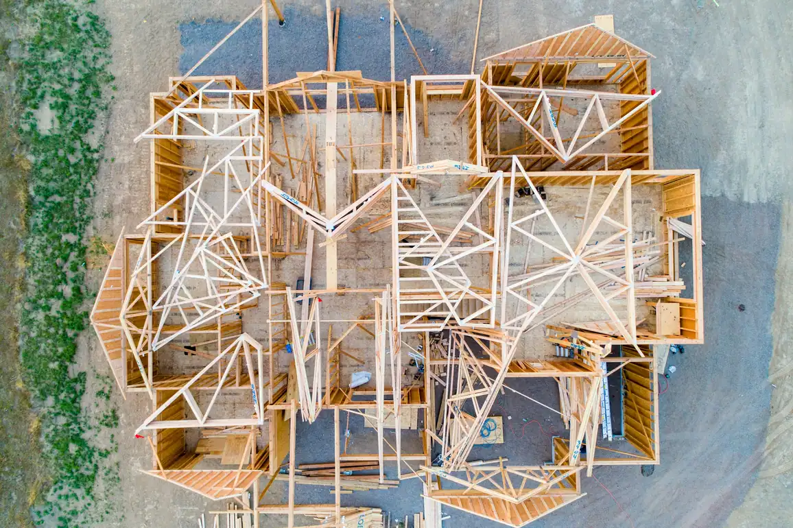 Aerial view of a timber-framed house with roof trusses going up