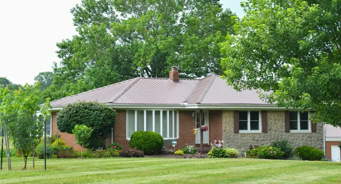 Single-story stone and brick ranch house with a metal roof and a wide lawn
